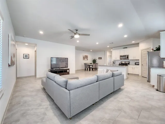 a living room with furniture a kitchen view and a refrigerator