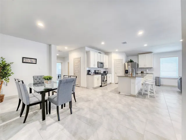 a view of kitchen with refrigerator stove dining table and chairs