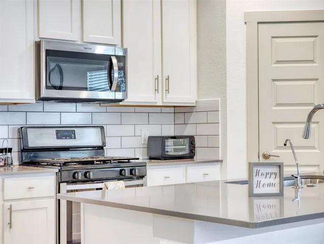 a kitchen with stainless steel appliances granite countertop a stove a microwave and a white cabinets