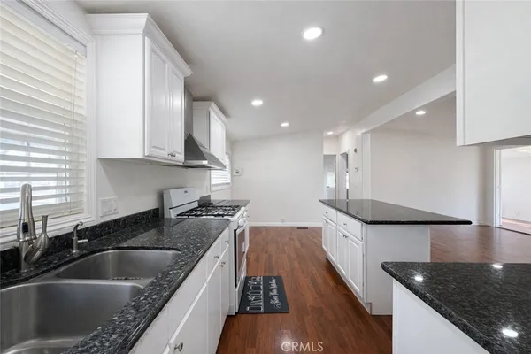 a kitchen with stainless steel appliances granite countertop a sink a stove and a wooden cabinets