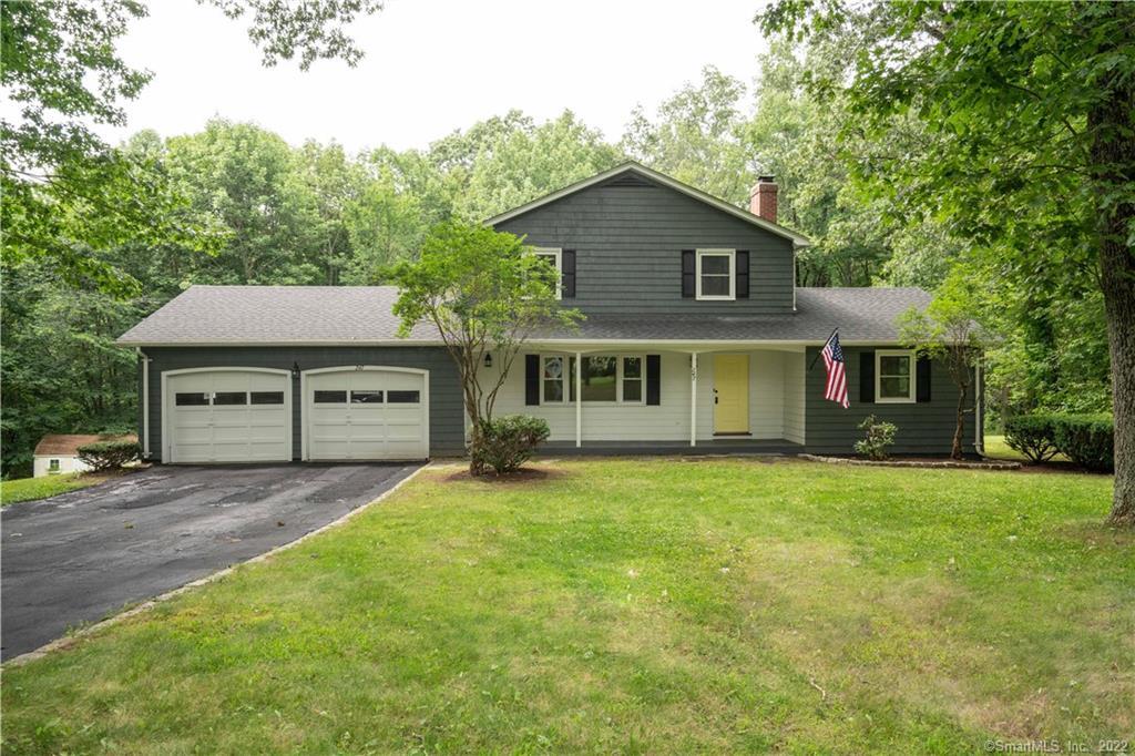 a front view of a house with a garden and trees
