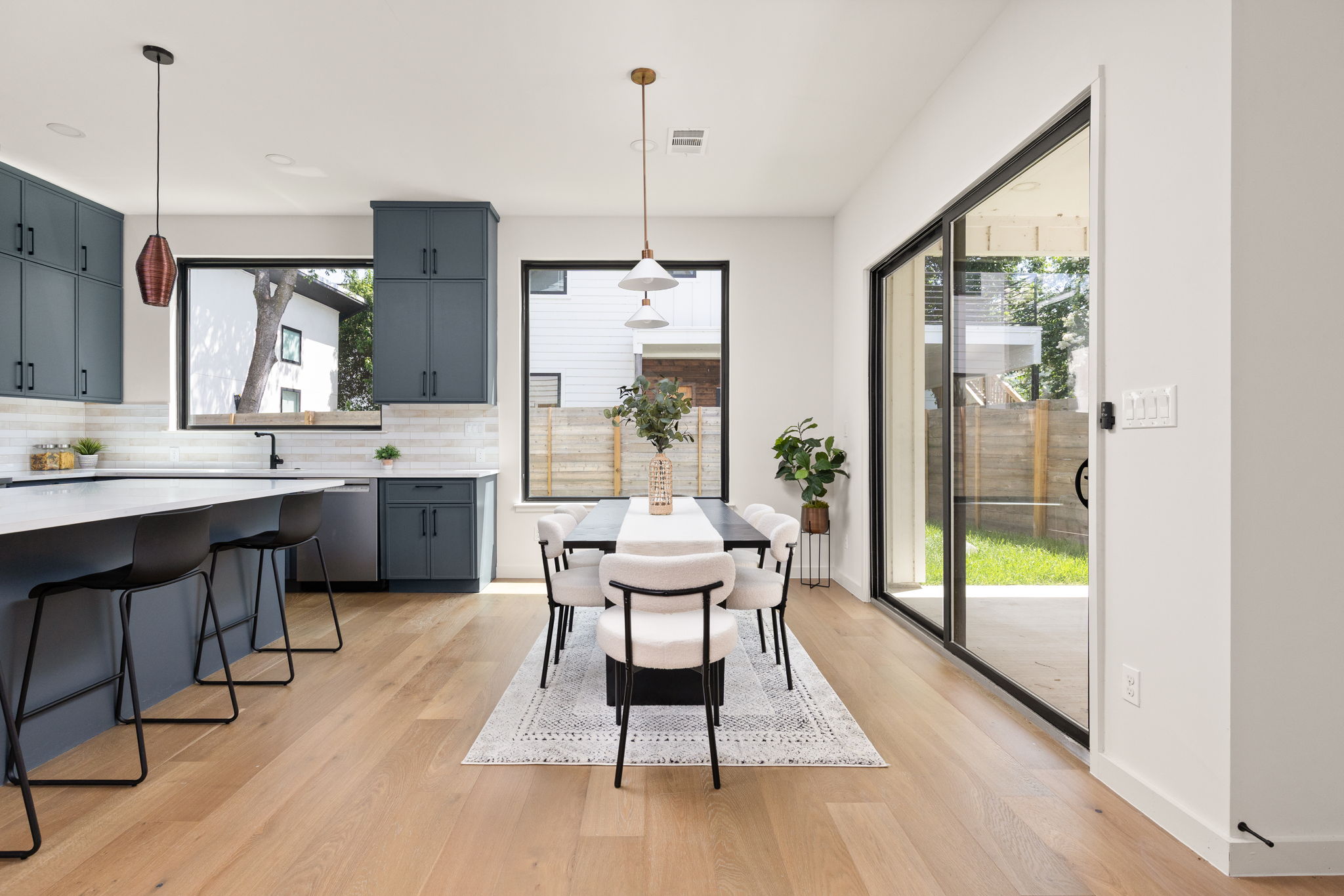 2717 Lyons Road, Unit 1 Austin, TX 78702 - Photo 14 of 40 An open-concept living space features a sleek kitchen island and a dining area, with abundant natural light from large windows and sliding glass doors.