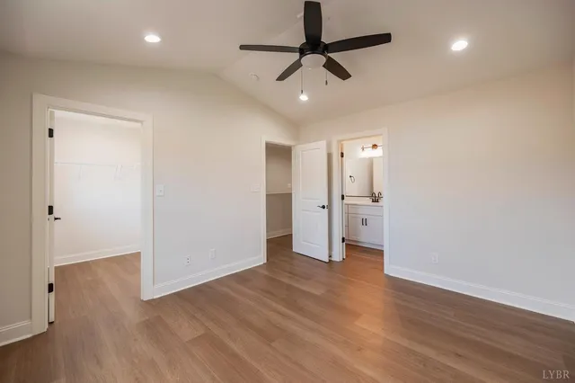 a view of an empty room with wooden floor and a ceiling fan