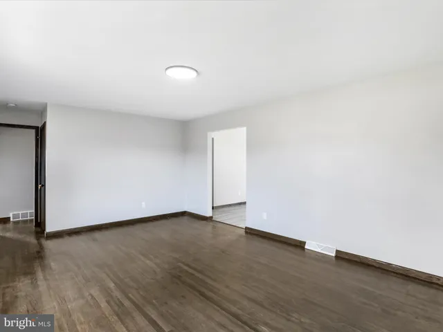 an empty room with wooden floor and white walls