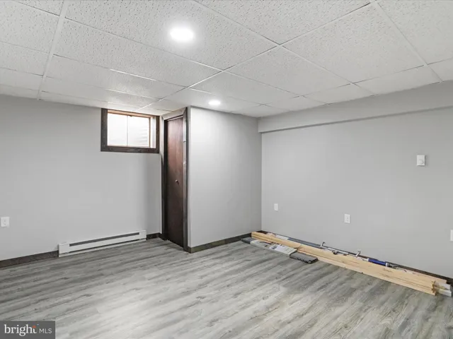 an empty room with wooden floor and windows with curtains