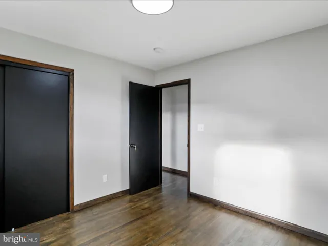 a view of an empty room with wooden floor and closet