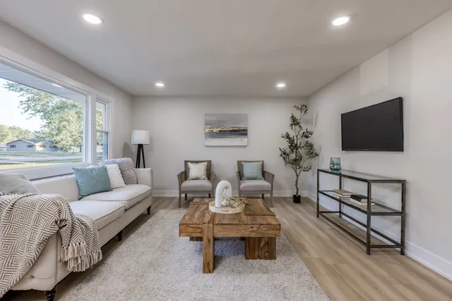 a living room with furniture a flat screen tv and a large window