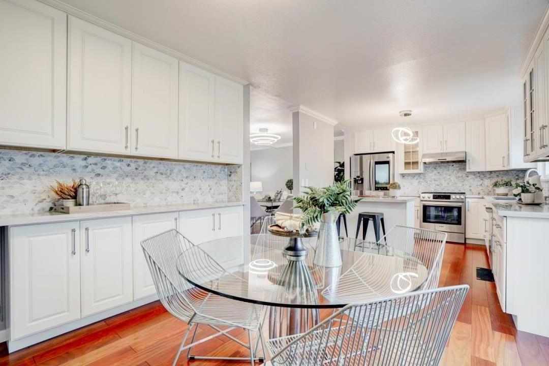 a kitchen with stainless steel appliances kitchen island granite countertop a table chairs and a stove