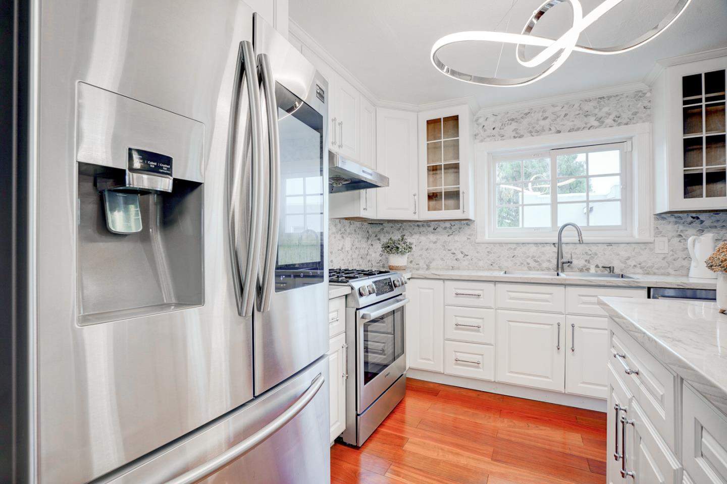 350 Buckingham Way Pacifica, CA 94044 - Photo 18 of 68 a kitchen with stainless steel appliances granite countertop a refrigerator a sink dishwasher a stove and white countertops with wooden floor