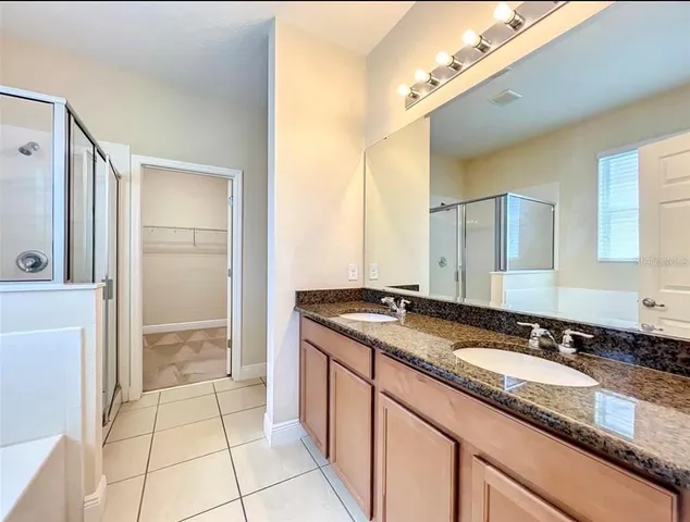 a bathroom with a granite countertop sink a mirror and a shower