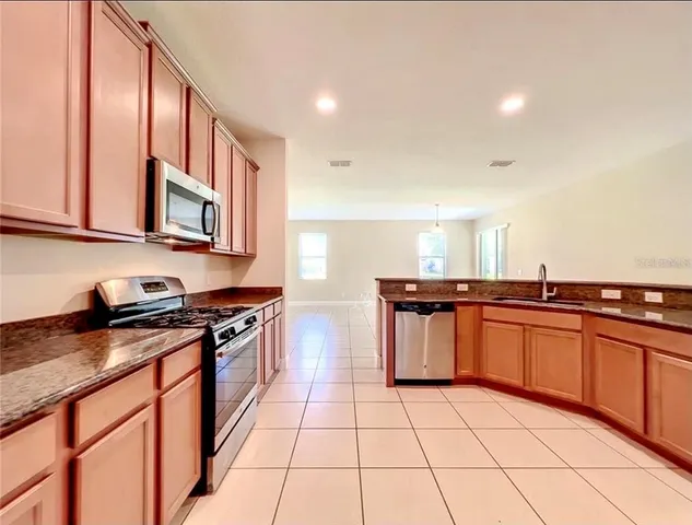 a kitchen with stainless steel appliances granite countertop a stove a sink and a microwave