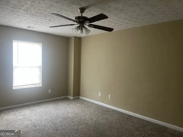 an empty room with a window and a fan