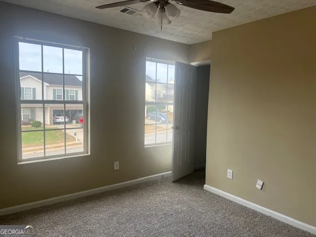 an empty room with windows and chandelier fan