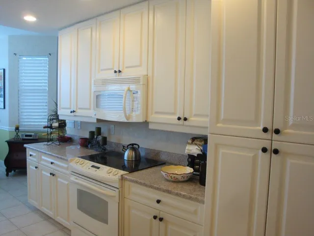 a kitchen with stainless steel appliances granite countertop white cabinets and white appliances