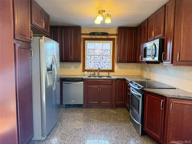 a kitchen with granite countertop stainless steel appliances a refrigerator and a sink