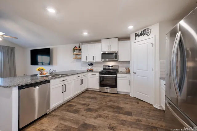 a kitchen with granite countertop a refrigerator stove and sink