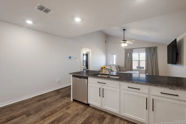 a kitchen with granite countertop a sink cabinets and wooden floor