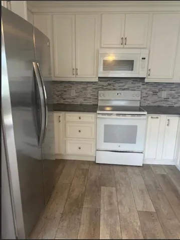 a kitchen with granite countertop white cabinets and stainless steel appliances