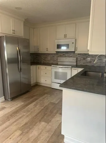 a kitchen with granite countertop a refrigerator sink and cabinets