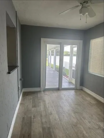 an empty room with chandelier fan and windows