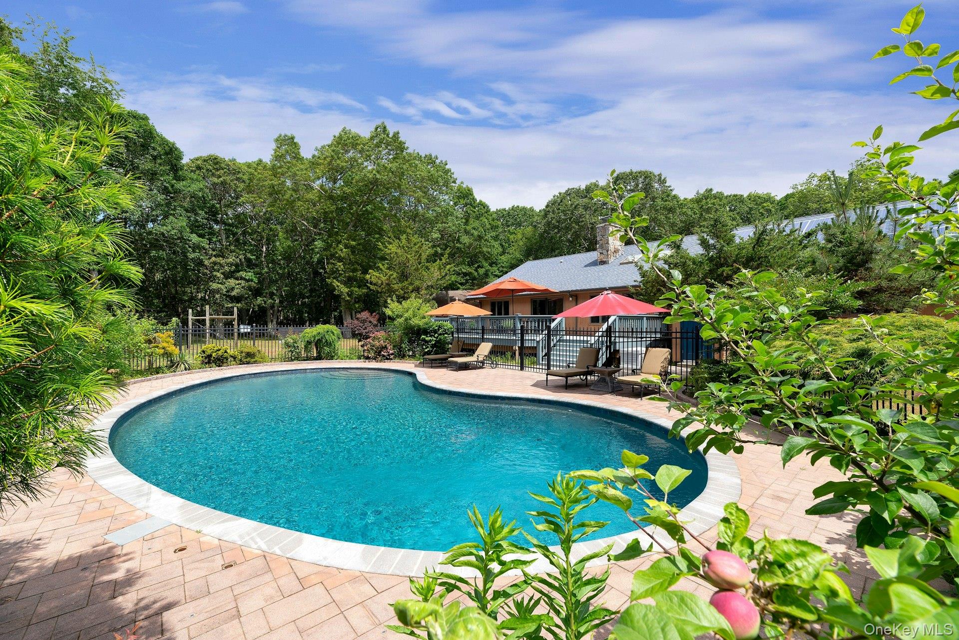 View of pool with view of wooded area and a patio area