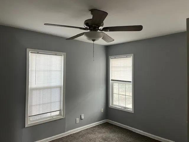 an empty room with a window and a fan