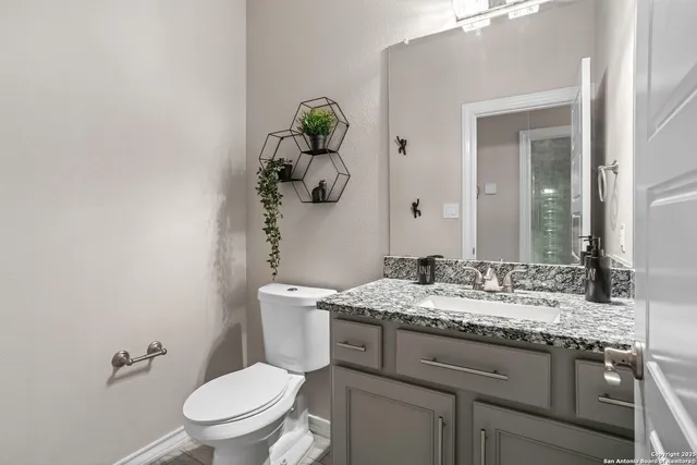 a bathroom with a granite countertop toilet sink and mirror