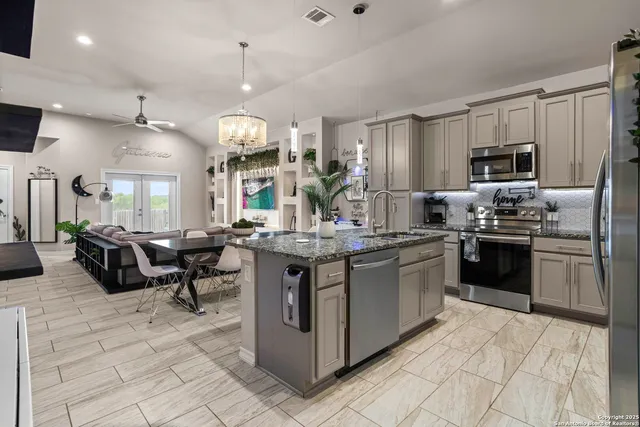 a kitchen with stainless steel appliances granite countertop a stove top oven a sink dishwasher a dining table and chairs