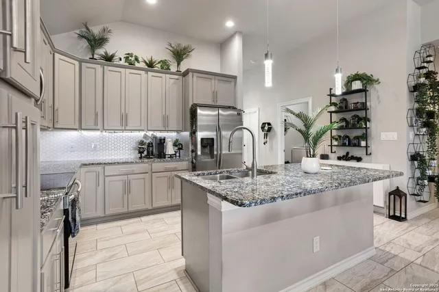 a kitchen with stainless steel appliances granite countertop a sink a stove and a refrigerator