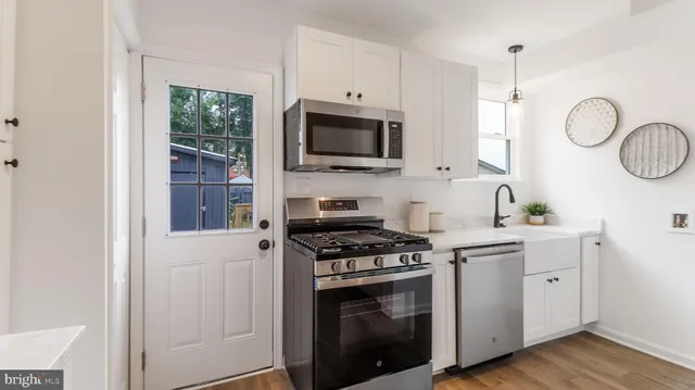 a kitchen with stainless steel appliances granite countertop a sink a stove a microwave and wooden cabinets