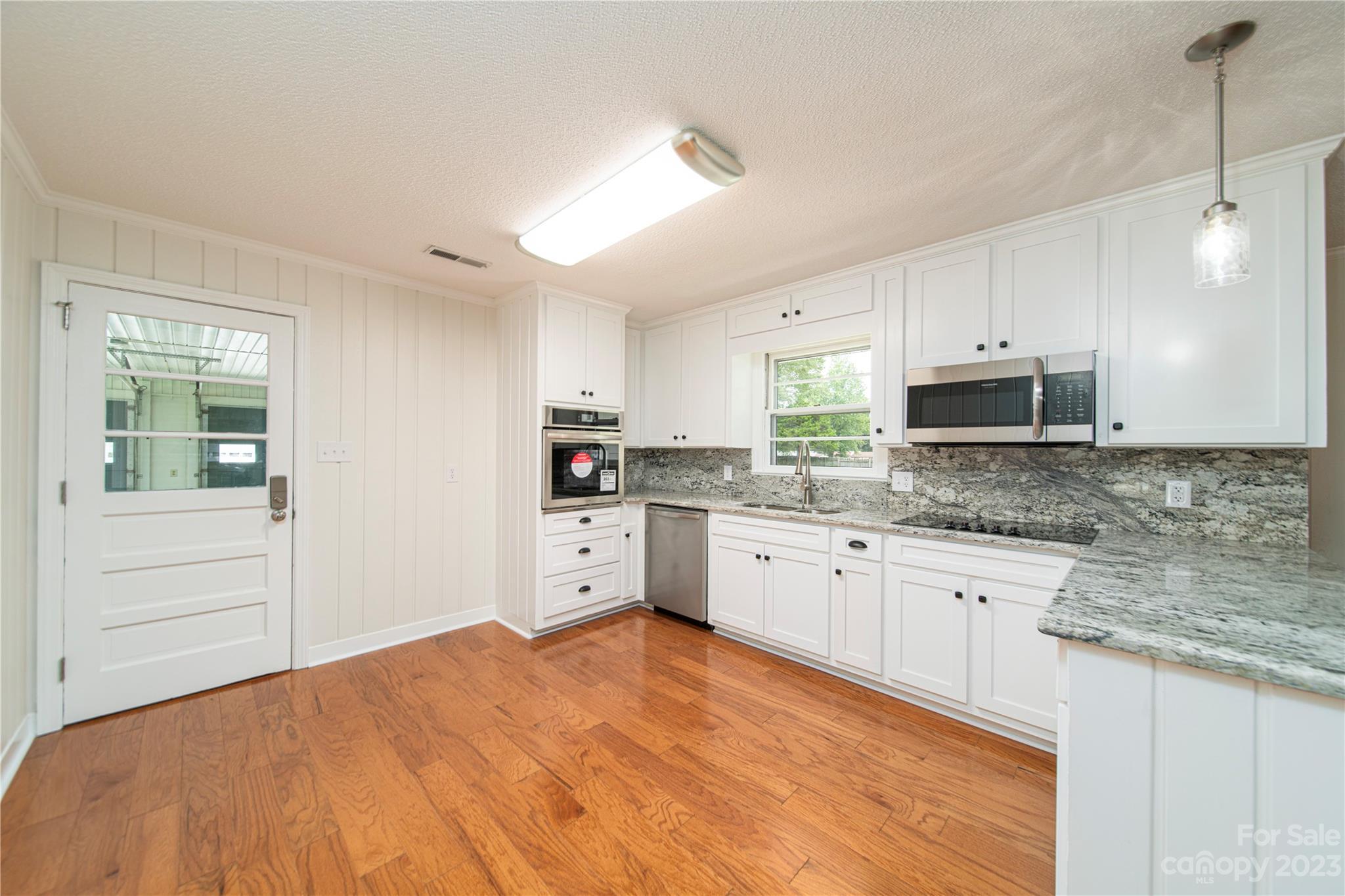 1253 Rainbow Road Advance, NC 27006 - Photo 24 of 46 a kitchen with granite countertop white cabinets and stainless steel appliances
