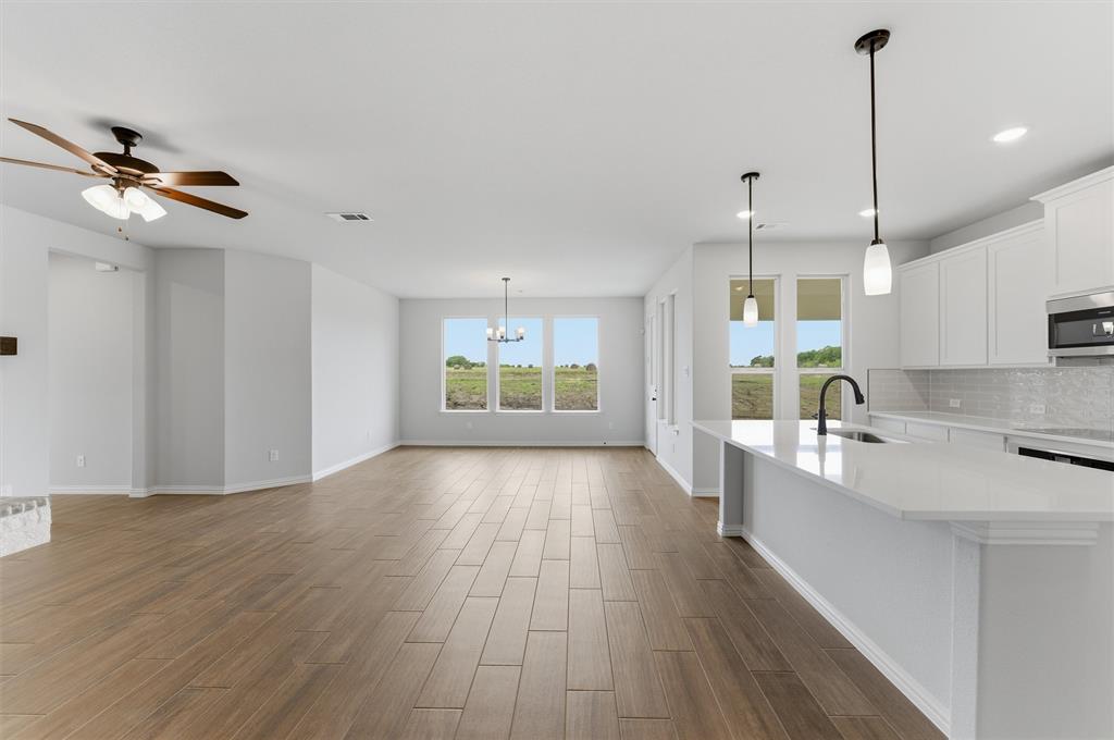 8911 County Road 623 Blue Ridge, TX 75424 - Photo 11 of 28 Kitchen featuring suspended lighting, wood tiled floors, a center island with sink, white cabinets, and light stone countertops
