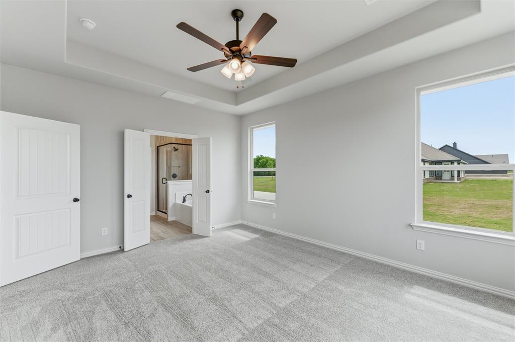 8911 County Road 623 Blue Ridge, TX 75424 - Photo 21 of 28 Unfurnished bedroom with a tray ceiling, ensuite bathroom, light carpet, and ceiling fan