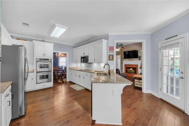a living room with stainless steel appliances furniture a flat screen tv and a fireplace