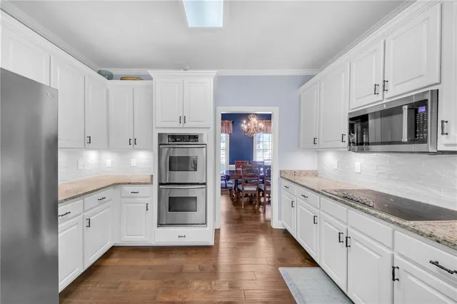 a kitchen with granite countertop white cabinets and stainless steel appliances
