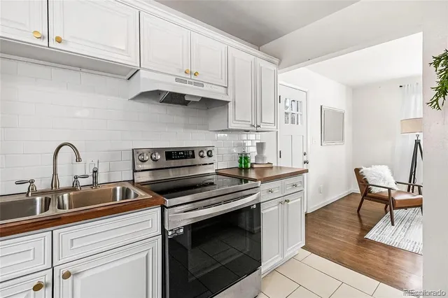 a kitchen with stainless steel appliances granite countertop a stove white cabinets a sink and dishwasher
