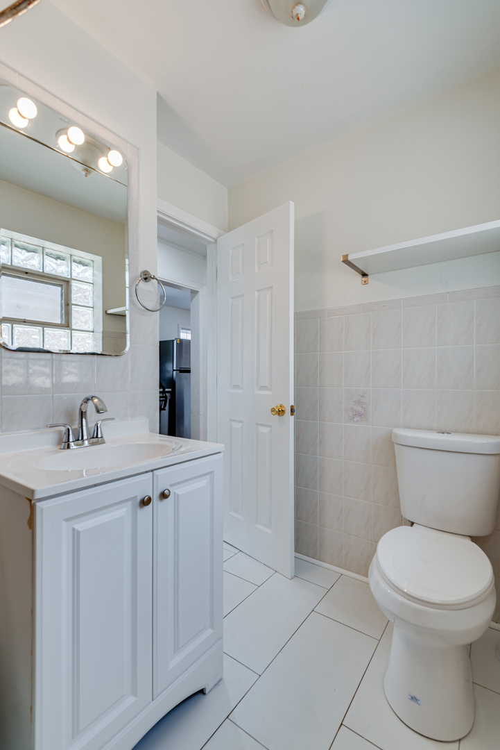 7004 West Foster Avenue Chicago, IL 60656 - Photo 8 of 16 a bathroom with a toilet a sink a mirror and vanity