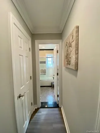 a view of a hallway with wooden floor and a bathroom
