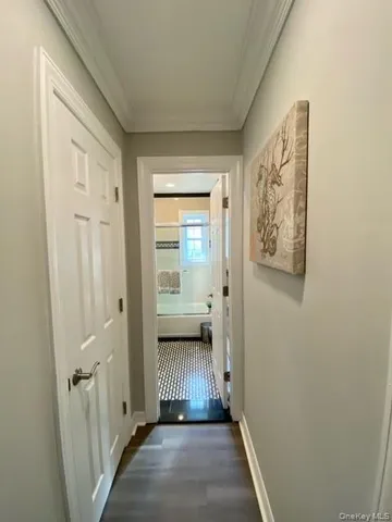 a view of a hallway with wooden floor and a bathroom