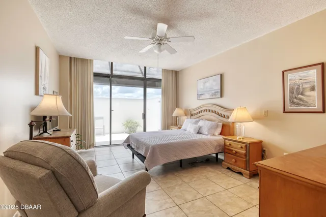 a spacious bedroom with a bed a dresser and a chandelier