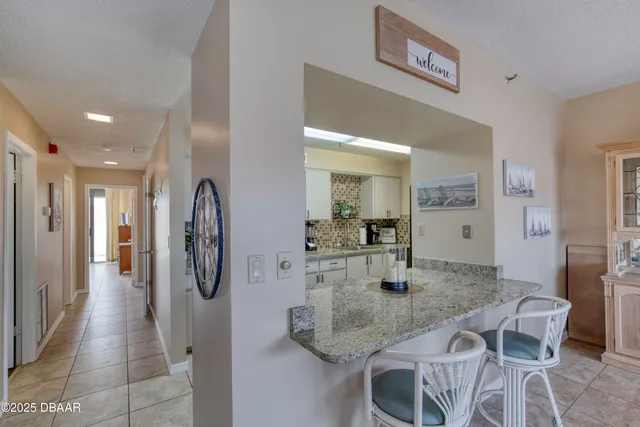 a kitchen with stainless steel appliances granite countertop a dining table chairs and refrigerator