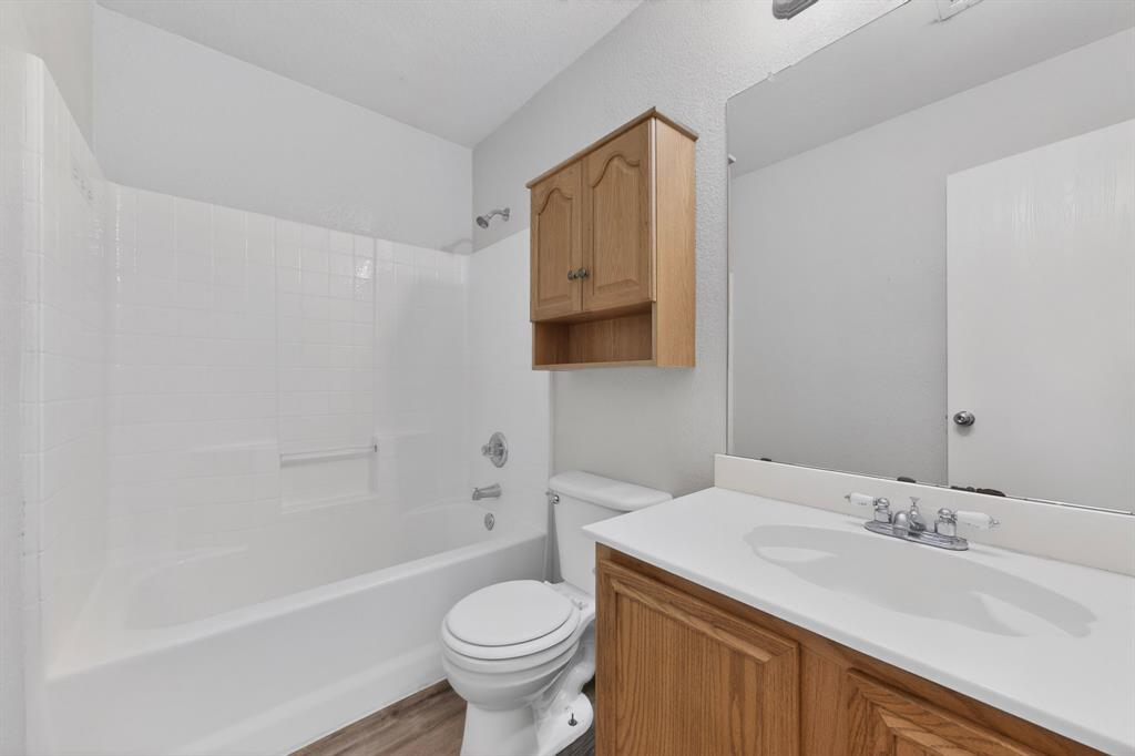 3401 Newgate Street Midlothian, TX 76065 - Photo 17 of 34 Bathroom featuring a white tub/shower combination, wood-finish vanity with a white countertop, and wood-finish wall-mounted cabinetry