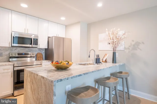 a kitchen with stainless steel appliances granite countertop a sink a stove a refrigerator cabinets and a dining table