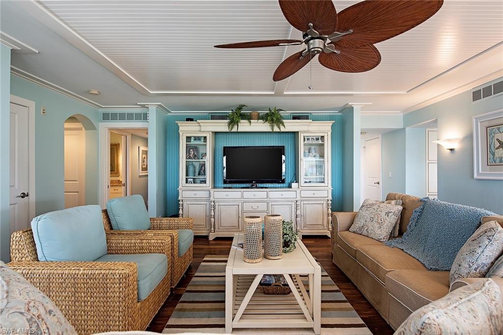 9155 Gulf Shore Drive, Unit 401 Naples, FL 34108 - Photo 5 of 12 a living room with furniture a flat screen tv and a chandelier