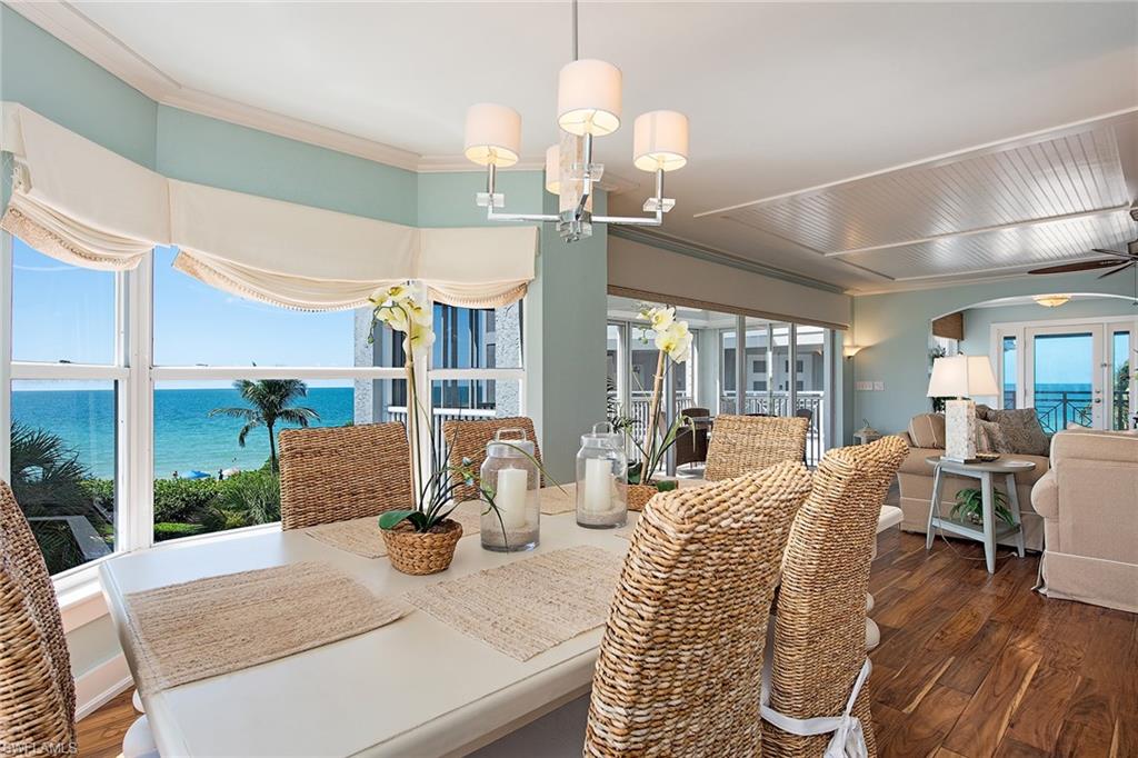 9155 Gulf Shore Drive, Unit 401 Naples, FL 34108 - Photo 8 of 12 a view of a dining room with furniture wooden floor and chandelier