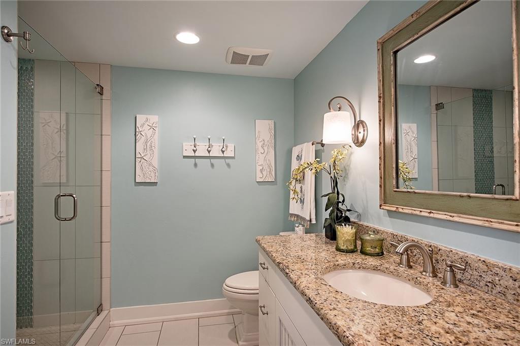 9155 Gulf Shore Drive, Unit 401 Naples, FL 34108 - Photo 10 of 12 a bathroom with a granite countertop sink a toilet and shower