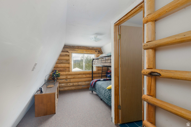 23 Scare Canyon, Unit 23 Logan, UT 84321 - Photo 11 of 33 Room featuring sloped ceilings, a window with exterior scenery, log wall construction, and carpeting