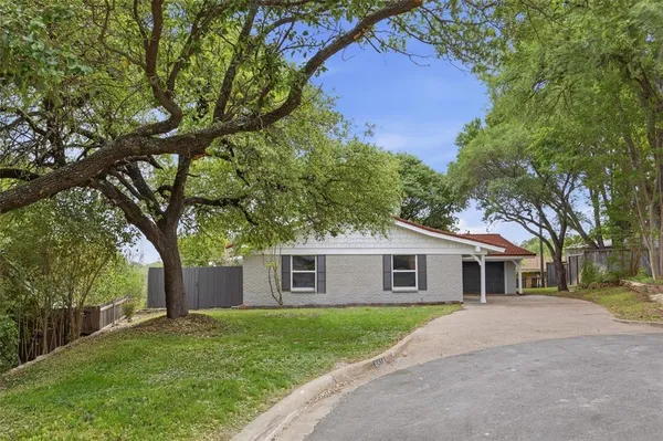 a front view of a house with a garden and trees