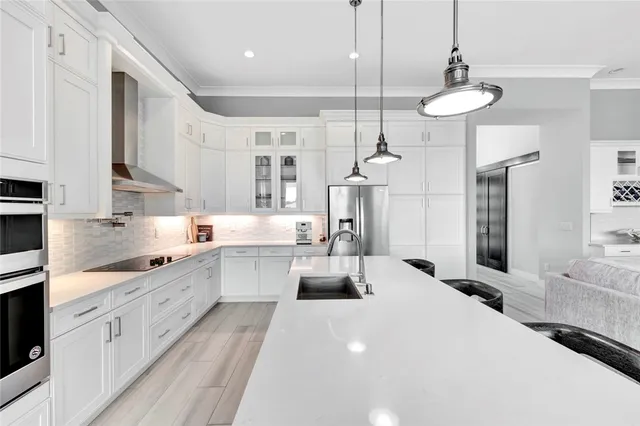 a large white kitchen with lots of counter space wooden floor and stainless steel appliances