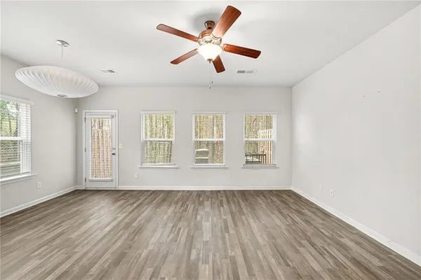 a view of an empty room with wooden floor and a window